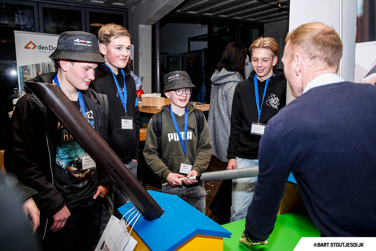 Jongeren voeren een doe-opdracht uit met buizen bij een miniatuurhuisje op Werkend Altena