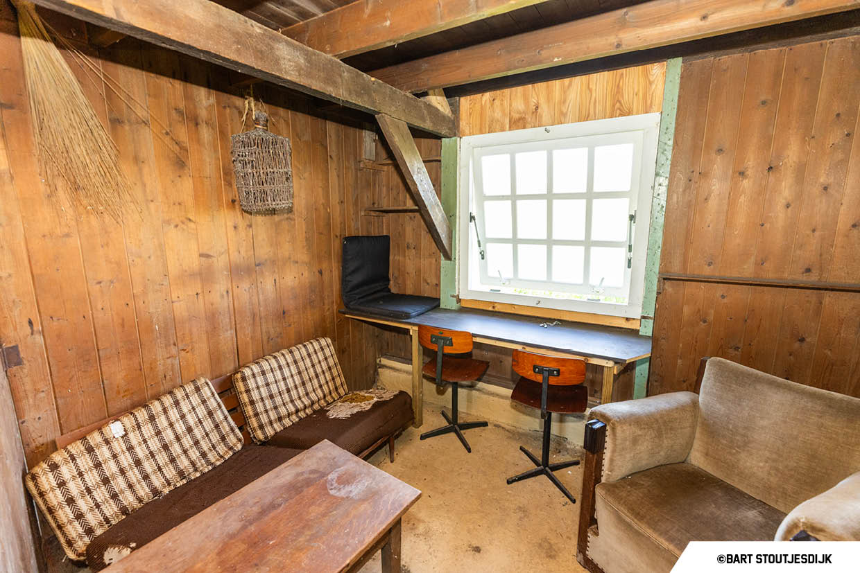Interieur van een keet met houten wanden, zithoek en raam