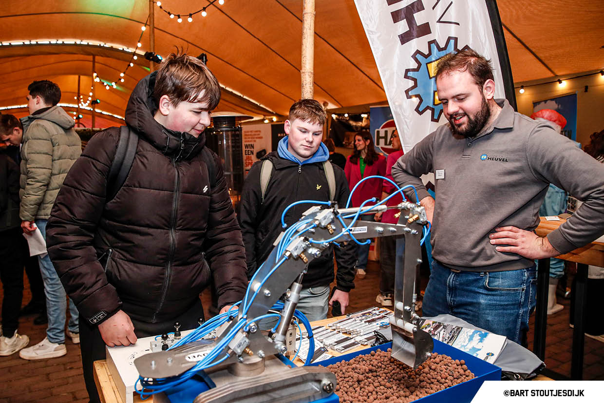 Bezoekers krijgen uitleg bij een model van een minigraafmachine op Werkend Altena