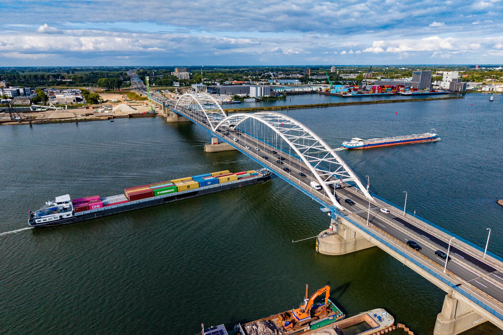 Dronefoto van een brug over de rivier met binnenvaartschepen