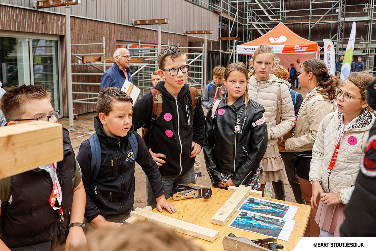 Jongens kijken naar houtbewerking aan een werkbank tijdens de Onderwijsdag