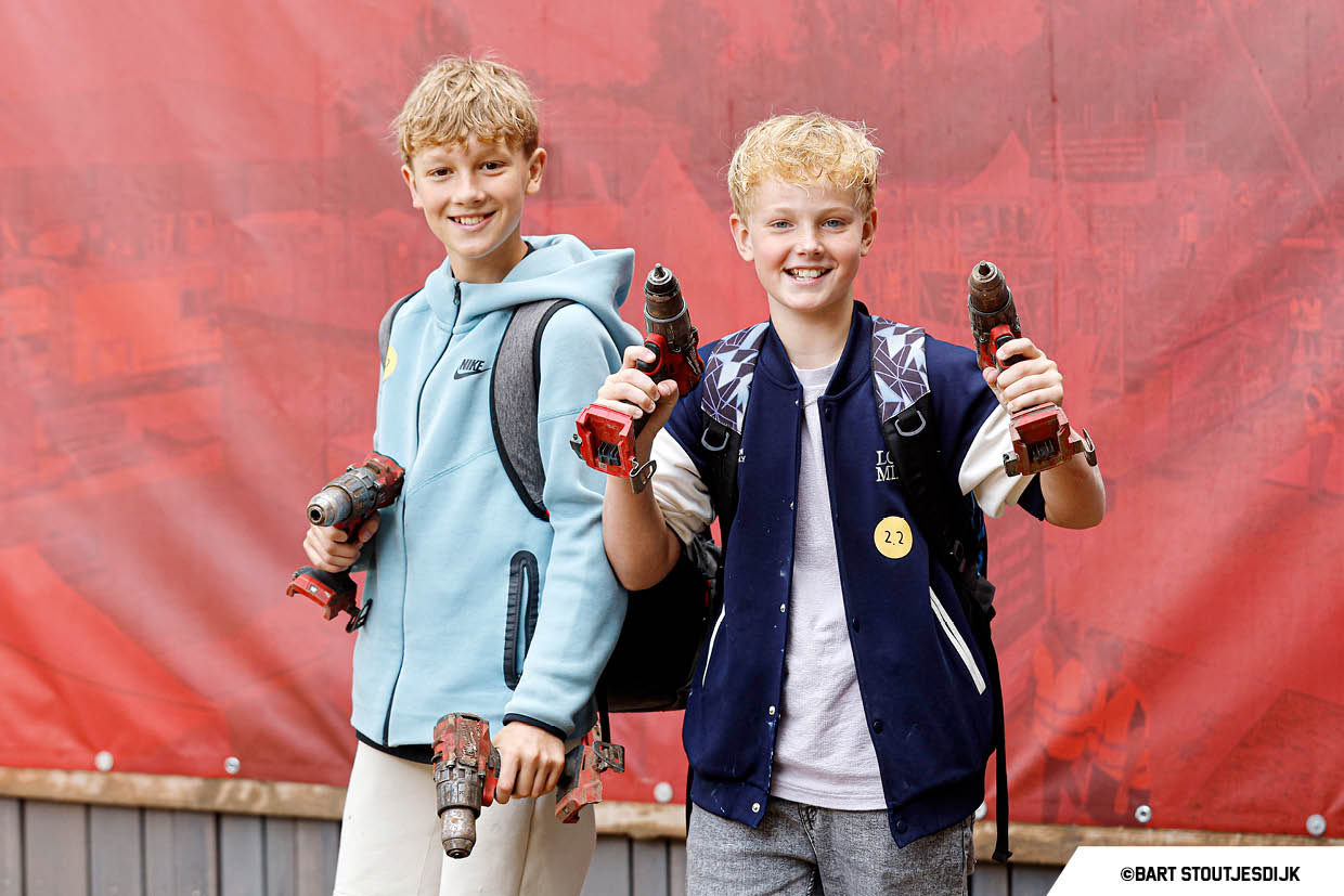 Twee jongens poseren glimlachend met een boormachine tijdens de Onderwijsdag