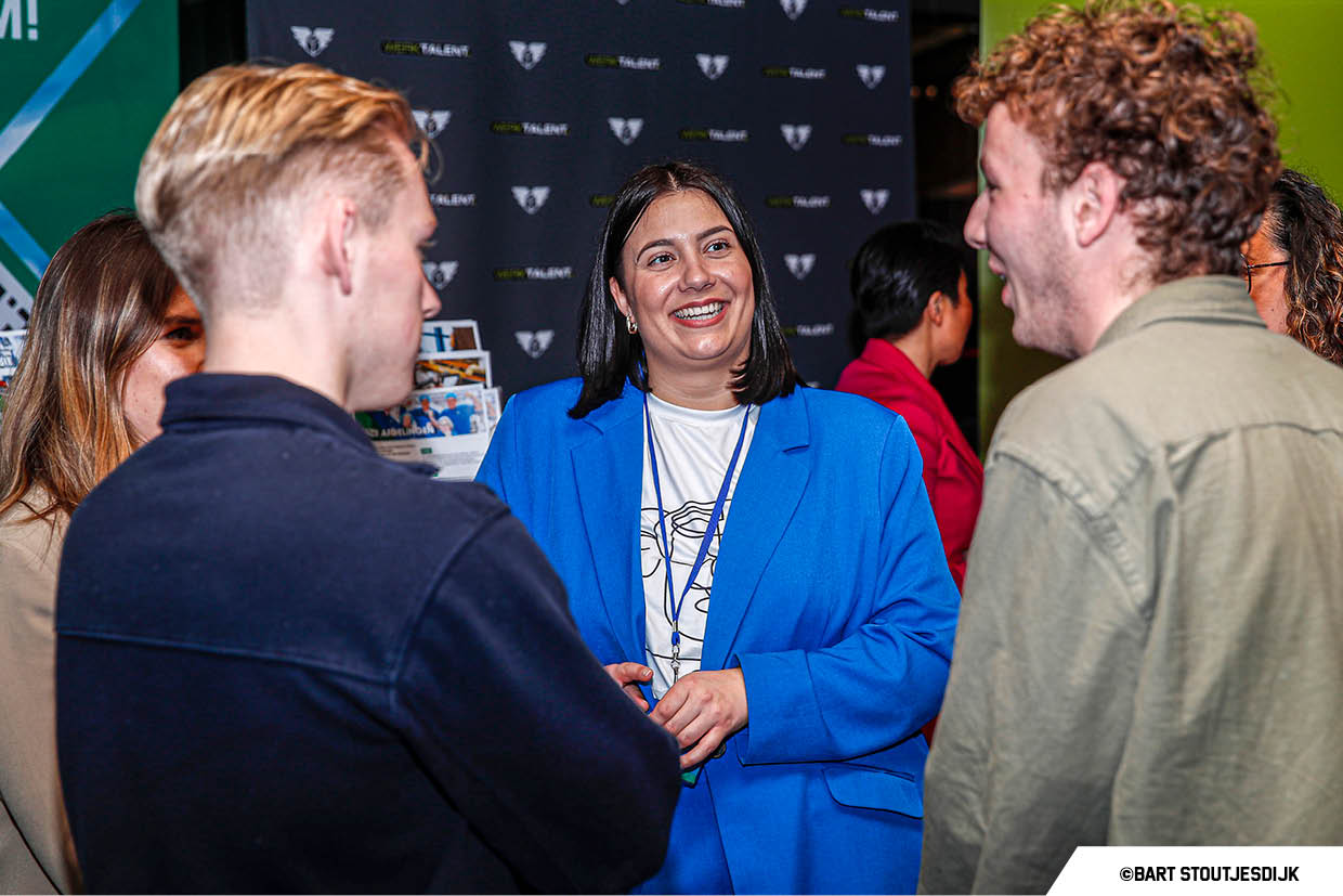 Een vrouw gaat in gesprek met jongeren bij een stand op Werkend Altena