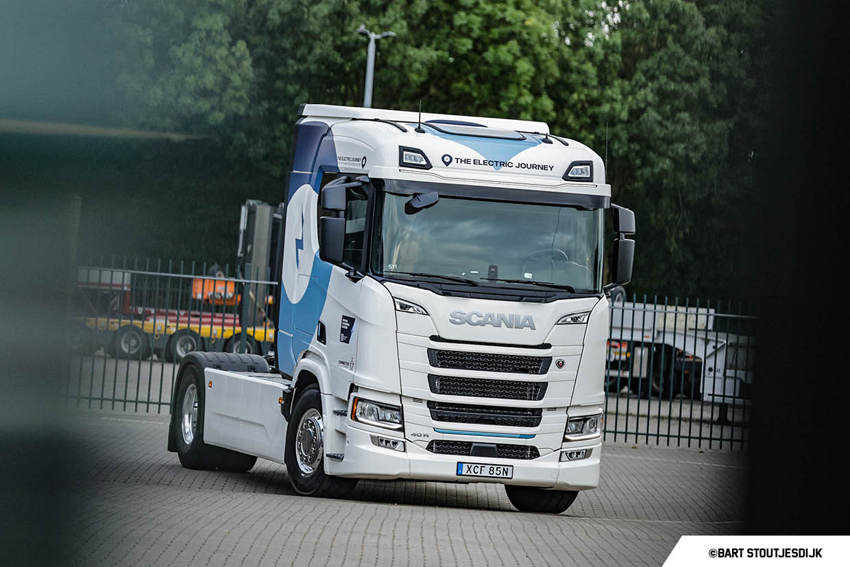 Witte elektrische Scania-vrachtwagen met de tekst The Electric Journey op een buitenterrein