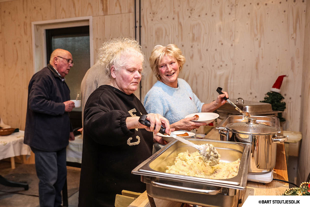 Bezoekers scheppen stamppot van een warm buffet tijdens een winterse bijeenkomst