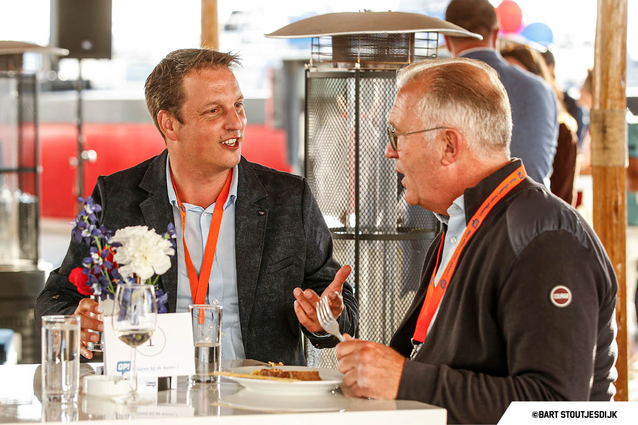 Twee mannen in gesprek aan een statafel op het terras van Gangboordpraat