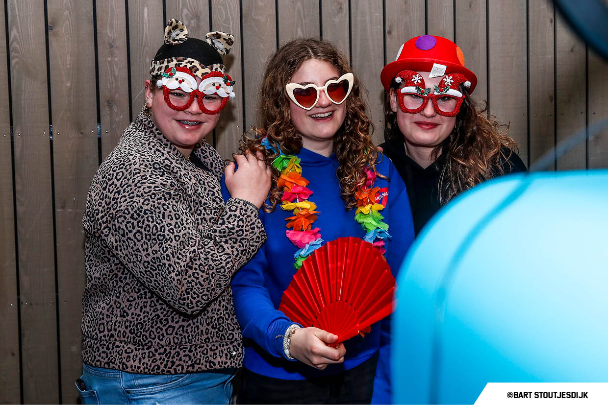 Drie lachende bezoekers poseren met verkleedbrillen bij de photobooth op Werkend Altena