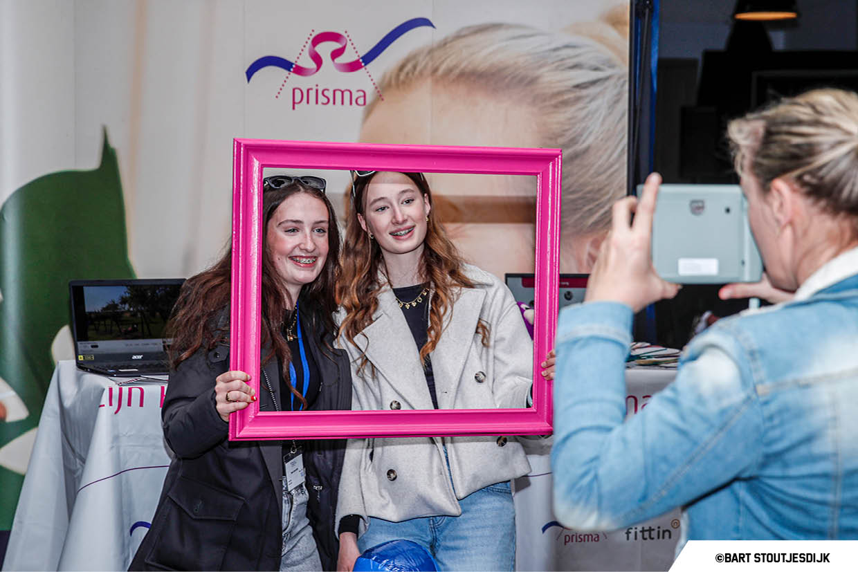 Twee meiden poseren lachend achter een roze fotolijst op Werkend Altena