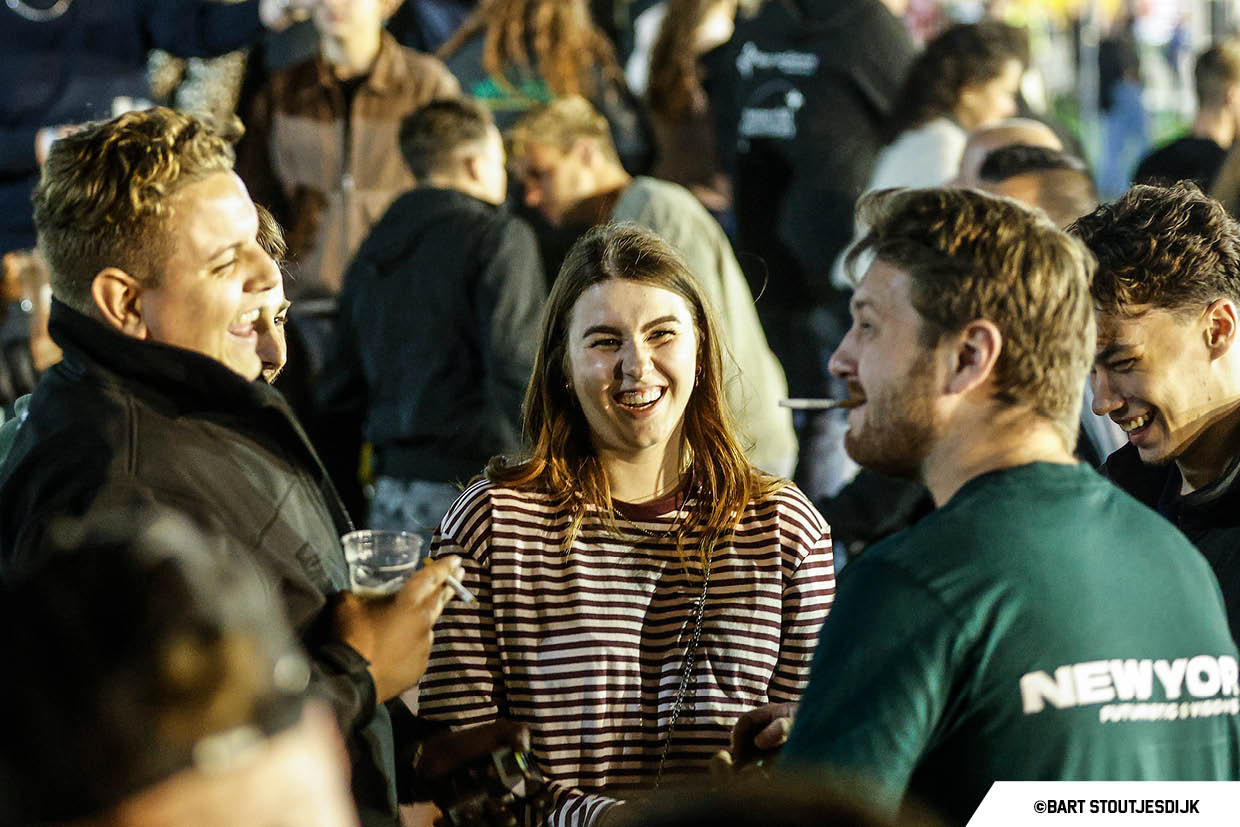 Jongeren kletsen en proosten tijdens een buitenfestival in de avond